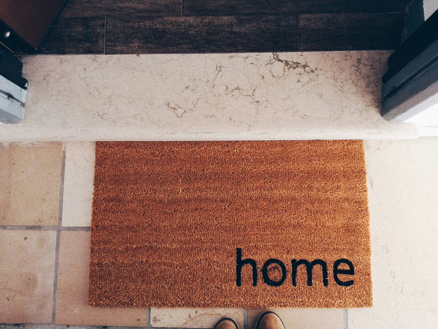 A welcome mat that reads home, just inside an apartment doorway